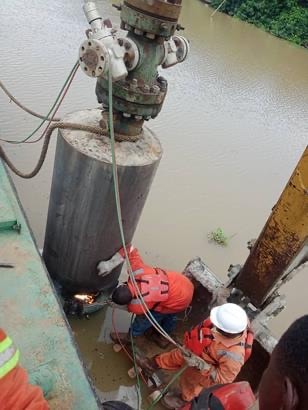 Crew cutting casing beneath a wellhead from a barge