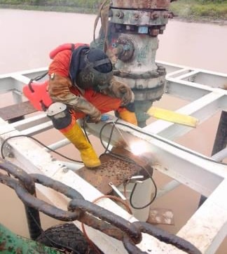 Welder joining platform steel beside a wellhead